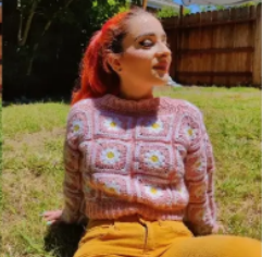 Model wearing a pink daisy granny-square crochet sweater outdoors